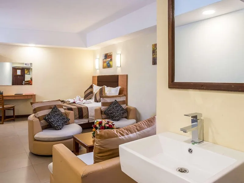 Notranjost sobe v hotelu Premium Inn z zakonsko posteljo in sedežno garnituro.